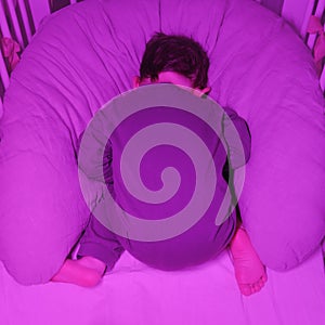 Toddler baby sleeps face down on his stomach while lying in a crib. Fu