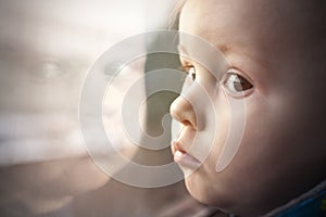 Toddler with big eyes in reflection of window.