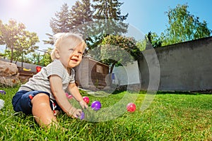 Toddler blond boy play with balls on the grass