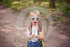 Toddler blond child, eating wild blueberries in forest