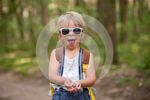 Toddler blond child, eating wild blueberries in forest