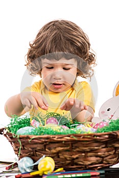 Toddler boy arrange Easter eggs in basket photo