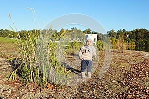 Toddler boy in autumn clothes by big grass