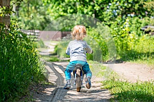 Toddler boy with balance bike at countryside fields forests