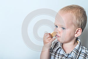 Toddler boy in blue shorts and shirt eating cookies close-up and copy space