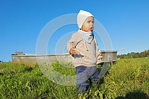 Toddler boy with bread on meadow by boat