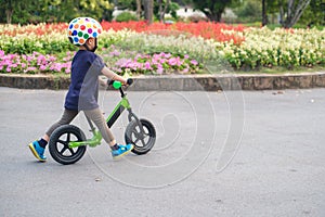 Toddler boy child wearing safety helmet learning to ride first balance bike