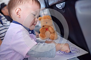 Toddler boy coloring in coloring book with crayons during flight on airplane