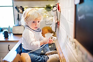 Toddler boy in dangerous situation at home. Child safety concept.
