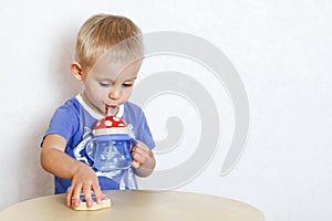 Toddler boy drinking water from a kids drinker with a straw