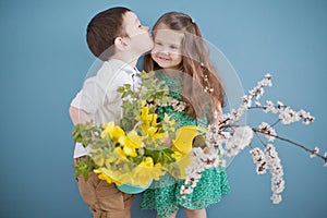 Toddler boy and girl holding daffodills and apricot blossom branches