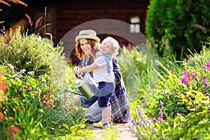 Toddler boy and his mother watering plants in the garden