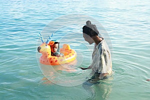 Toddler boy on inflating ring swimming with mom in sea