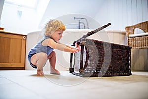 Toddler boy with a laundry basket in the bathroom.