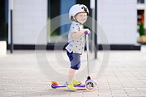 Toddler boy learning to ride scooter