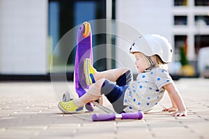 Toddler boy learning to ride scooter