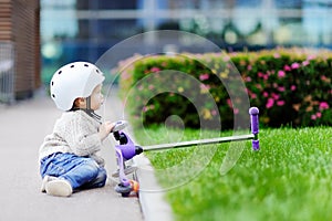 Toddler boy learning to ride scooter