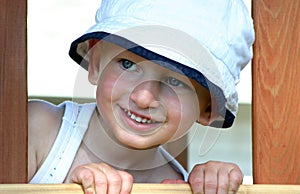 Toddler boy peeking out of window