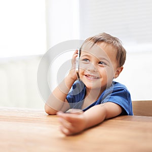 Toddler, boy and phonecall at home, happiness and communication with technology. Table, calling and conversation for