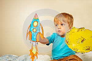 Toddler boy play astronaut holding paper rocket