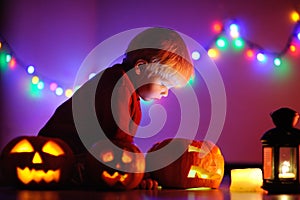 Toddler boy playing with halloween pumpkins indoors