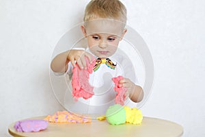 A toddler boy playing with kinetic pasticine, a great activity to develop fine motor skills
