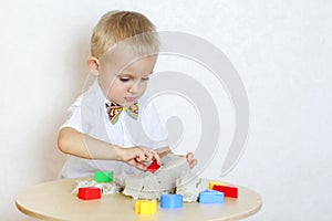 A toddler boy playing with kinetic sand, a great activity to develop fine motor skills