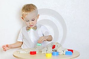 A toddler boy playing with kinetic sand, a great activity to develop fine motor skills