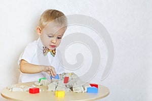 A toddler boy playing with kinetic sand, a great activity to develop fine motor skills