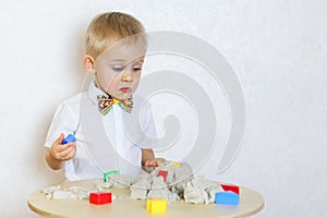 A toddler boy playing with kinetic sand, a great activity to develop fine motor skills