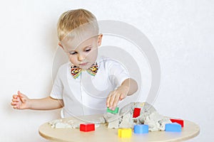 A toddler boy playing with kinetic sand, a great activity to develop fine motor skills