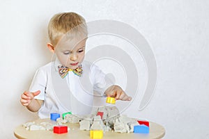 A toddler boy playing with kinetic sand, a great activity to develop fine motor skills