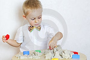 A toddler boy playing with kinetic sand, a great activity to develop fine motor skills