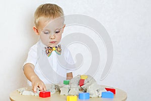 A toddler boy playing with kinetic sand, a great activity to develop fine motor skills