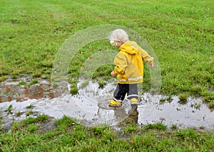Toddler boy playing in a muddy puddle after the rain