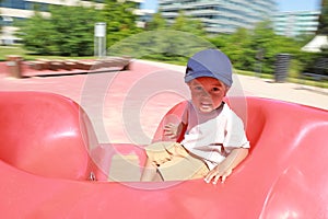 Toddler boy playing on playground - marry go round