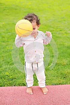 Toddler boy playing on playground - throwing orange ball