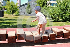 Toddler boy playing on playground - unstable wooden bridge