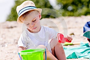 Toddler boy playing with sand sifter on a beach