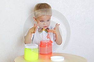 A toddler boy playing with slime, not happy with his dirty hands