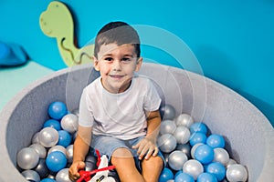 Toddler boy playing with a toy in a ball pit full of colorful balls. Exercise sensory system while being mindful