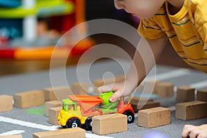 Toddler boy playing with a toy and wooden blocks on the floor in the children\'s room