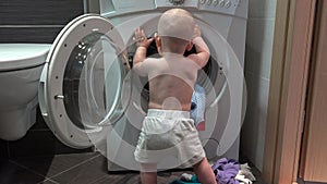 Toddler boy playing with washing machine in bathroom