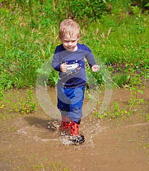 Toddler boy playing in water puddles photo