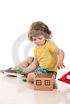 Toddler boy playing with wood house toy photo
