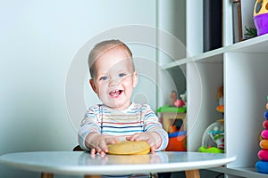 Toddler boy playing yellow plasticine Play-Doh in playroom close-up and copy space