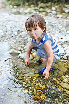 Toddler boy plays in flashy river