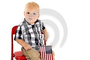 Toddler boy in a red chair holding an American flag