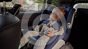 Toddler boy riding in car and looking out of the open window. Concept of kids traveling, baby safety, children going by car.