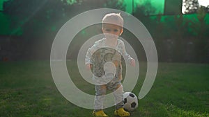 Toddler boy runs away after kicking soccer ball at sunlight